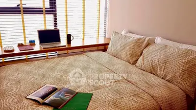 Cozy bedroom with natural light and modern decor, featuring a laptop and books on a wooden desk.