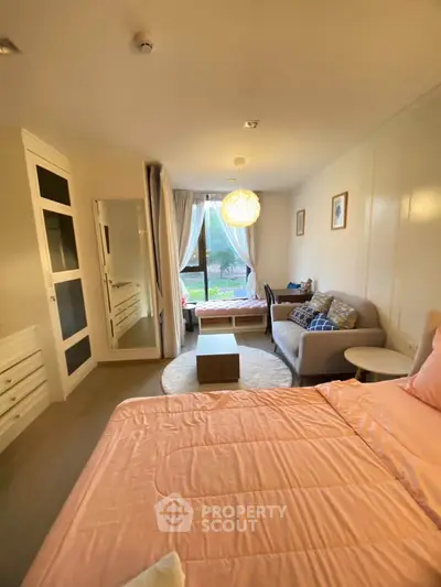 Cozy bedroom with large window and stylish decor, featuring a comfortable bed and seating area.