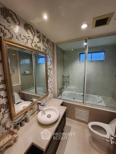 Modern bathroom with elegant mosaic tiles and glass-enclosed bathtub, featuring a sleek vanity and contemporary fixtures.