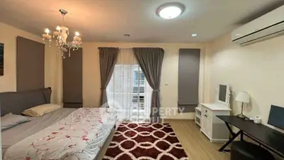 Spacious bedroom with elegant chandelier and modern decor, featuring a cozy bed and stylish workspace.