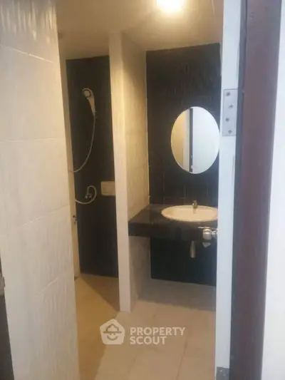 Modern bathroom with sleek black and white design, featuring a round mirror and contemporary fixtures.