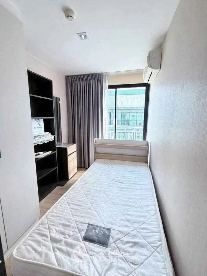 Cozy bedroom with single bed, modern decor, and large window offering natural light.