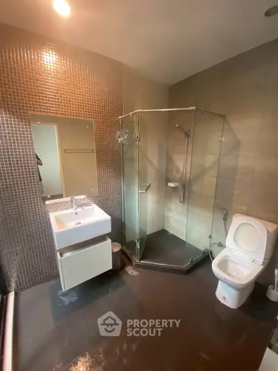 Modern bathroom with glass shower and sleek fixtures in contemporary apartment.