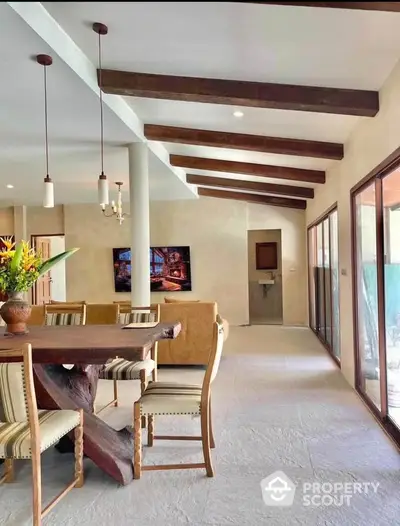 Spacious open-plan living room with rustic wooden beams and modern decor