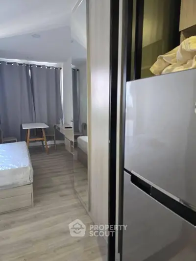 Modern bedroom with mirrored wardrobe and sleek refrigerator, perfect for urban living.