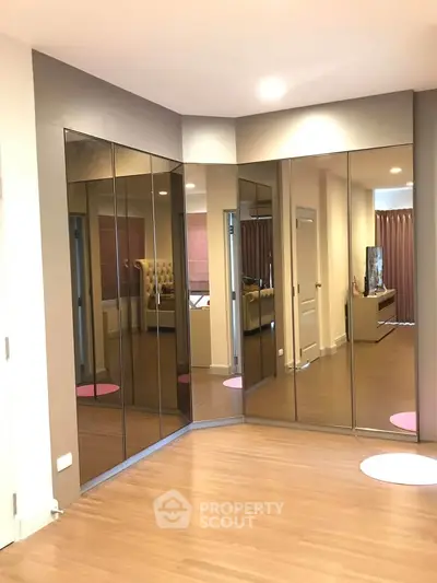 Spacious modern living room with mirrored walls and wooden flooring