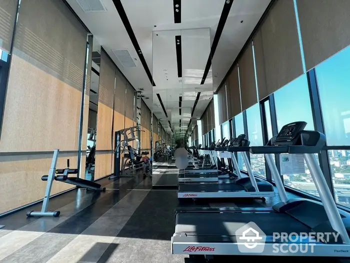 Luxurious high-rise gym with panoramic city views and modern fitness equipment.