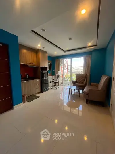 Modern living room with open kitchen and stylish furniture, featuring large windows and natural light.