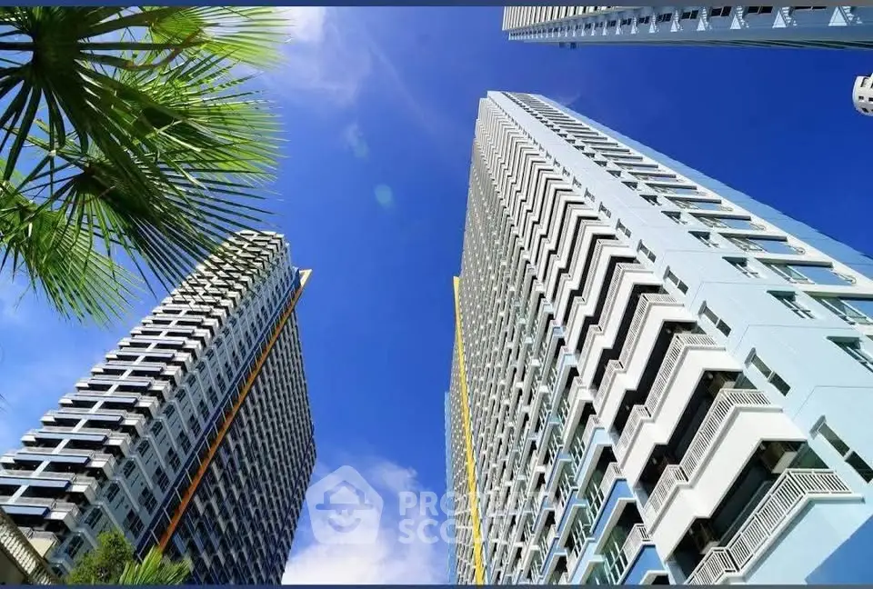 Stunning modern high-rise buildings with clear blue sky and palm trees, perfect urban living.
