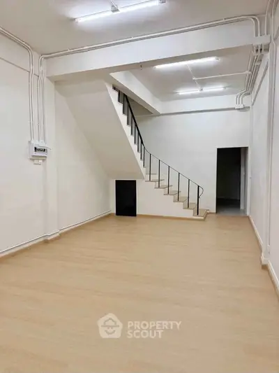 Spacious interior with modern staircase and wooden flooring, ideal for creative living or office space.