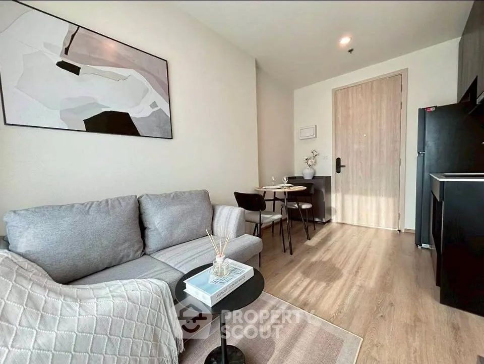 Modern living room with cozy gray sofa, stylish decor, and compact dining area in a chic apartment.