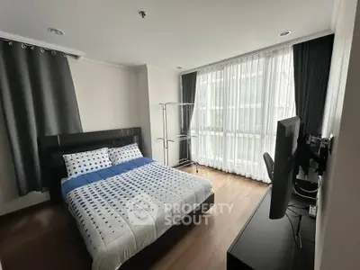 Modern bedroom with large window, stylish decor, and ample natural light in a contemporary apartment.