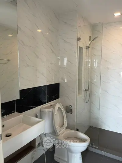 Modern bathroom with sleek design, featuring a glass shower and elegant fixtures.