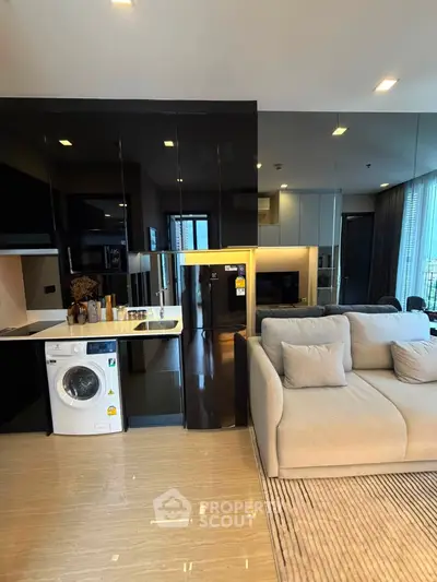 Modern living room with sleek kitchen, washing machine, and cozy sofa in stylish apartment.
