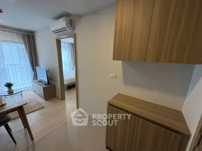 Modern apartment interior with open living room and bedroom view, featuring sleek wooden cabinetry and air conditioning.