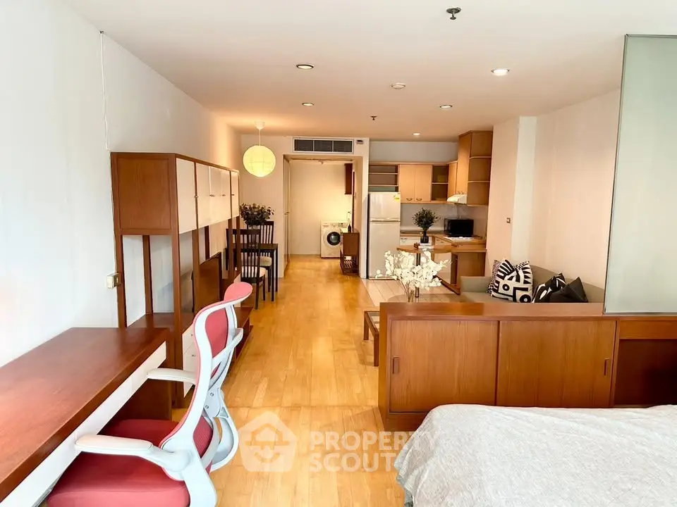 Spacious open-plan apartment with modern furnishings and wooden flooring, featuring a cozy living area and kitchen.