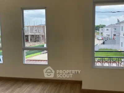 Spacious room with large windows offering a view of ongoing construction and neighborhood.