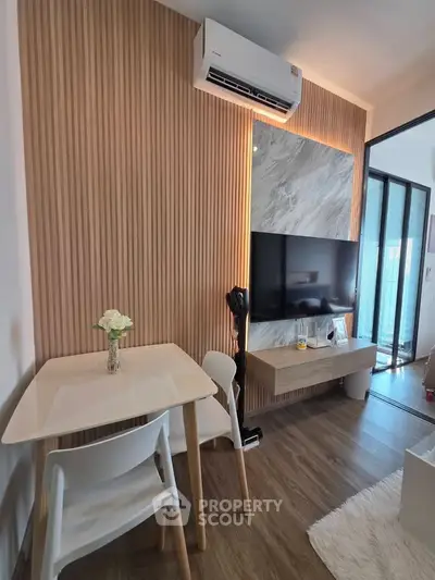 Modern living room with stylish wood paneling and sleek furniture, featuring a mounted TV and air conditioning.