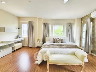 Spacious and bright bedroom with elegant decor and large windows.