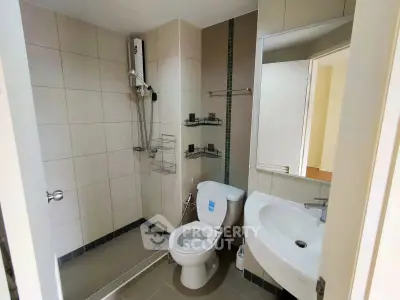 Modern bathroom with sleek fixtures and neutral tiles, featuring a shower and toilet.