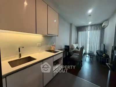 Modern open-layout kitchen and living room with sleek cabinetry and cozy seating area.