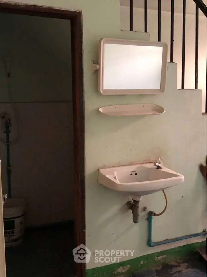 Simple bathroom with wall-mounted sink and mirror, showcasing basic plumbing and minimalistic design.