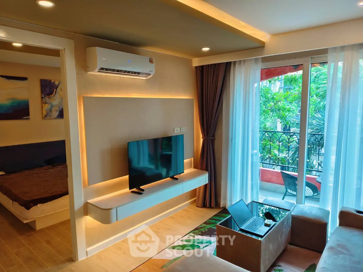 Modern living room with balcony view, featuring sleek TV setup and cozy seating area.