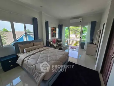 Spacious bedroom with balcony and modern decor in a bright, airy setting.