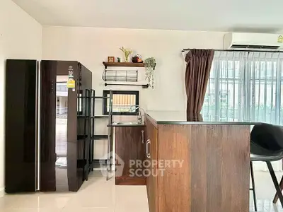Modern kitchen with sleek appliances and breakfast bar in bright, airy space.