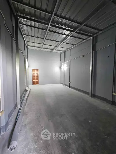 Spacious industrial-style room with high ceilings and metal roof, ideal for storage or workshop use.