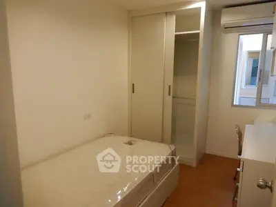 Cozy minimalist bedroom with built-in wardrobe and air conditioning, perfect for urban living.