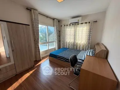 Bright bedroom with large windows and modern furnishings, featuring a wooden floor and ample natural light.