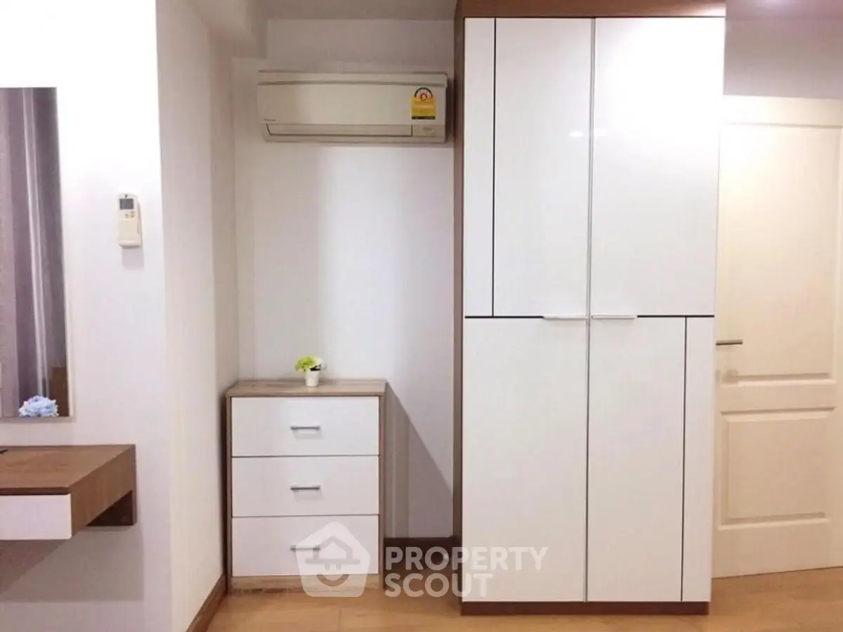 Modern bedroom with sleek white wardrobe and air conditioning unit