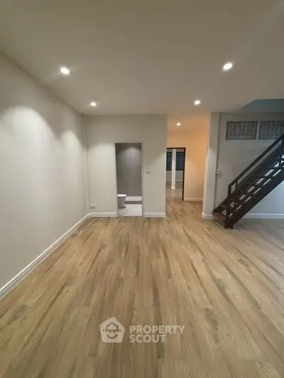 Spacious living room with wooden flooring and modern staircase in a stylish home.