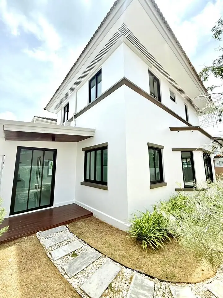 Modern white two-story house with sleek design and lush landscaping