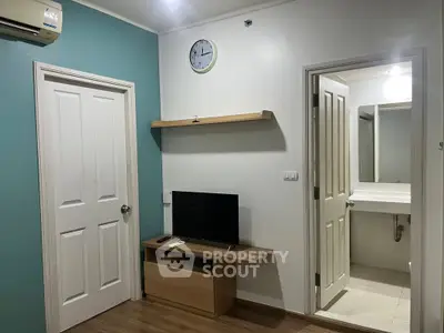 Modern apartment interior with TV, wooden flooring, and bathroom view