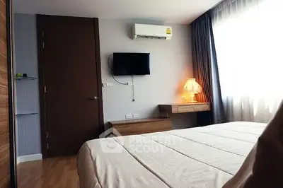 Cozy bedroom with natural light, modern furnishings, and air conditioning in a stylish apartment.