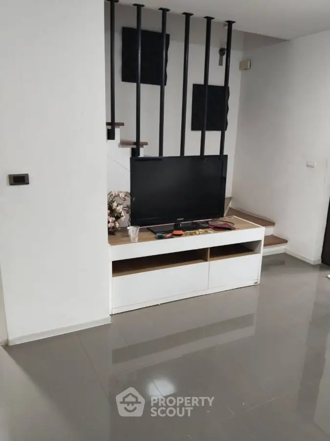 Modern living room with sleek TV stand and staircase accent