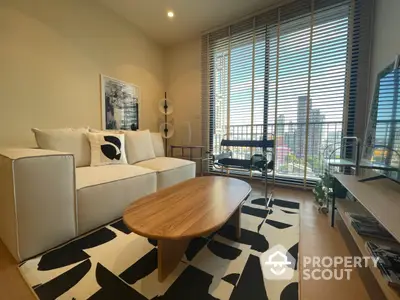 Chic modern living room with stylish white sofa, unique oval wooden table, and eye-catching black and white rug, complemented by natural light.