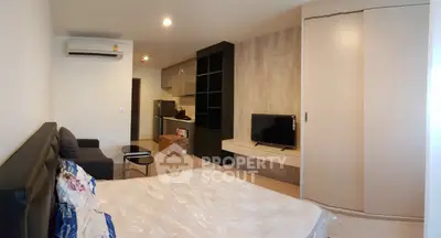 Modern bedroom with built-in wardrobe and compact living area in stylish apartment.