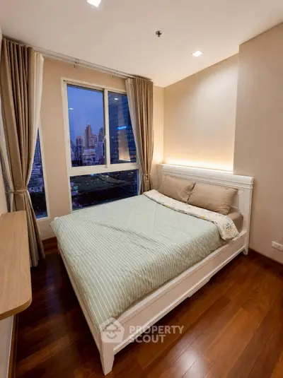 Modern bedroom with city view, featuring elegant wooden flooring and stylish decor.