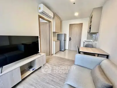 Modern living room with sleek furniture and compact kitchen in open layout apartment.