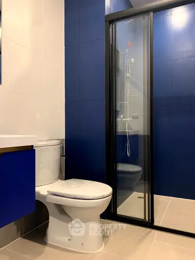 Modern bathroom with sleek blue and white design featuring a glass shower enclosure.