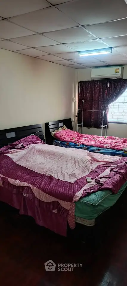 Cozy bedroom with two beds and natural light, perfect for restful nights.