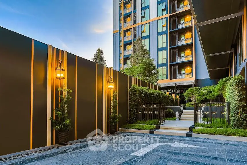 Luxurious modern building entrance with elegant lighting and lush greenery