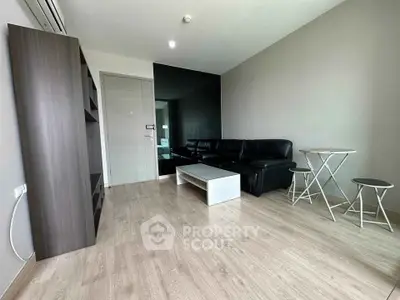 Modern living room with sleek black sofa and minimalist decor in a stylish apartment.
