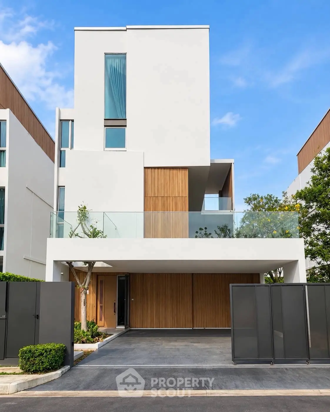 Modern minimalist three-story house with wooden accents and glass balcony in a serene neighborhood.