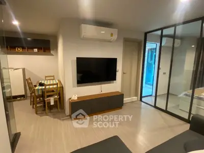Modern living room with glass partition and wall-mounted TV in stylish apartment.