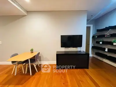 Modern living room with sleek TV setup and stylish dining area on wooden flooring.