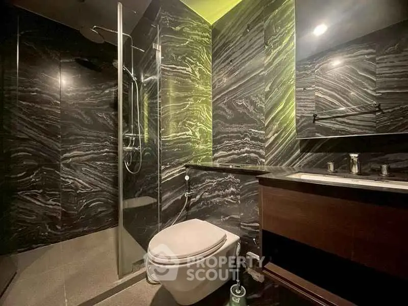 Luxurious modern bathroom with sleek black marble design and glass shower enclosure.